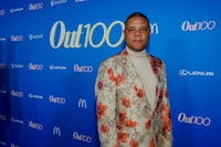 a man in a floral suit standing on a blue carpet